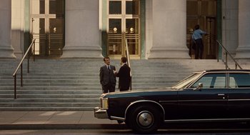 Movie still from “Milk” (2008), directed by Gus Van Sant – Two men in suits standing on the steps of a building; Wide shot, Over the shoulder angle