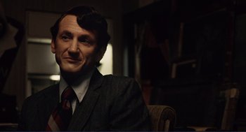 Movie still from “Milk” (2008), directed by Gus Van Sant – A man sitting in a chair wearing a suit and tie; Close Up shot, Over the shoulder angle