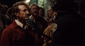 Movie still from “Milk” (2008), directed by Gus Van Sant – A police officer is talking to a man in a crowd of onlookers; Medium shot, Over the shoulder angle