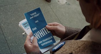 Movie still from “Milk” (2008), directed by Gus Van Sant – A person holding a pamphlet in front of a building; Close Up shot, Overhead angle