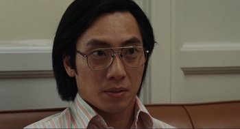 Movie still from “Milk” (2008), directed by Gus Van Sant – A person wearing glasses and a striped shirt; Close Up shot, Over the shoulder angle