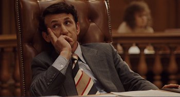 Movie still from “Milk” (2008), directed by Gus Van Sant – A man sitting in a chair with his chin resting on his hand; Medium shot, High angle