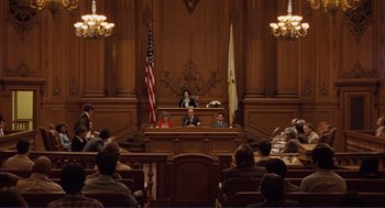 Movie still from “Milk” (2008), directed by Gus Van Sant – A court room filled with people sitting in chairs; Extreme Wide shot, High angle