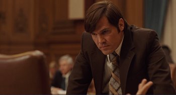 Movie still from “Milk” (2008), directed by Gus Van Sant – A man wearing a suit and tie sitting in a courtroom; Close Up shot, Low angle