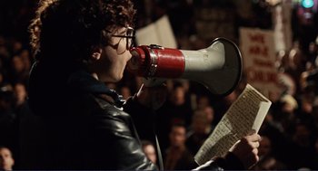 Movie still from “Milk” (2008), directed by Gus Van Sant – A person with a megaphone in front of a crowd of people; Medium shot, Low angle