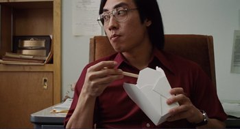 Movie still from “Milk” (2008), directed by Gus Van Sant – A man sitting at a table eating a box of food; Close Up shot, Low angle