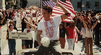 Movie still from “Milk” (2008), directed by Gus Van Sant – A man holding a bouquet of flowers in the back of a car; Medium shot, Low angle