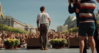Movie still from “Milk” (2008), directed by Gus Van Sant – A man standing on a stage in front of a crowd of onlookers; Wide shot, Low angle