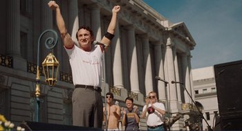 Movie still from “Milk” (2008), directed by Gus Van Sant – A group of people standing in front of a large building; Medium shot, Low angle