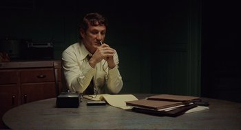 Movie still from “Milk” (2008), directed by Gus Van Sant – A man sitting at a table in front of papers; Medium shot, Low angle
