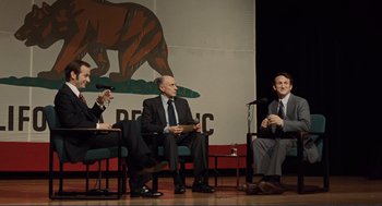 Movie still from “Milk” (2008), directed by Gus Van Sant – Three men in suits and ties sitting on chairs; Medium shot, Over the shoulder angle