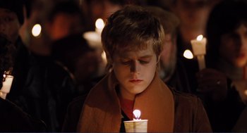 Movie still from “Milk” (2008), directed by Gus Van Sant – A young boy is holding a lit candle in front of a group of people; Close Up shot, Low angle