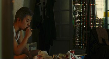 Movie still from “Millennium Mambo” (2001), directed by Hsiao-Hsien Hou – A man sitting at a table eating food; Medium shot, Over the shoulder angle