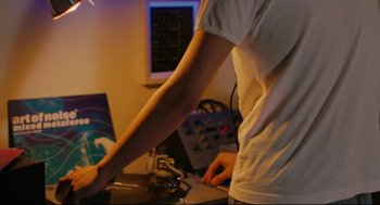 Movie still from “Millennium Mambo” (2001), directed by Hsiao-Hsien Hou – A person standing in front of a record player; Medium shot, Low angle