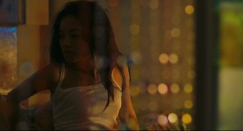 Movie still from “Millennium Mambo” (2001), directed by Hsiao-Hsien Hou – A woman in a white tank top standing in front of lights; Medium shot, Low angle