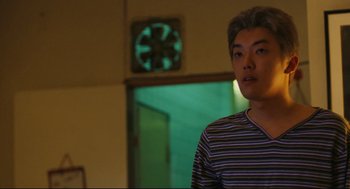 Movie still from “Millennium Mambo” (2001), directed by Hsiao-Hsien Hou – A man standing in front of a wall clock; Medium shot, Low angle