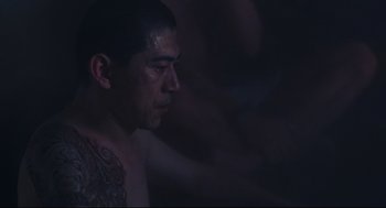 Movie still from “Millennium Mambo” (2001), directed by Hsiao-Hsien Hou – A man with a tattoo on his arm is looking into the distance; Close Up shot, Low angle