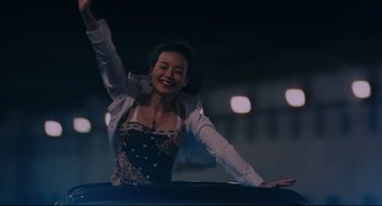 Movie still from “Millennium Mambo” (2001), directed by Hsiao-Hsien Hou – A woman in a black and white dress is waving; Medium shot, Low angle