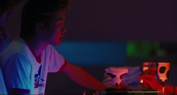 Movie still from “Millennium Mambo” (2001), directed by Hsiao-Hsien Hou – A young boy is looking at a glowing object in a dark room; Medium shot, Low angle