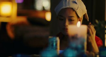 Movie still from “Millennium Mambo” (2001), directed by Hsiao-Hsien Hou – A woman with a towel wrapped around her head looking at a candle; Close Up shot, Over the shoulder angle