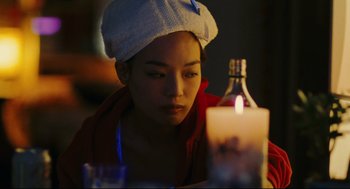 Movie still from “Millennium Mambo” (2001), directed by Hsiao-Hsien Hou – A woman with a towel on her head looking at a lit candle; Close Up shot, Over the shoulder angle