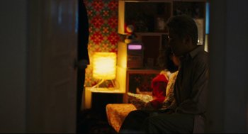 Movie still from “Millennium Mambo” (2001), directed by Hsiao-Hsien Hou – A man sitting on a chair in front of a fire place; Medium shot, Over the shoulder angle