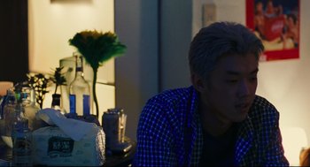 Movie still from “Millennium Mambo” (2001), directed by Hsiao-Hsien Hou – A man sitting at a table in a living room; Close Up shot, Over the shoulder angle