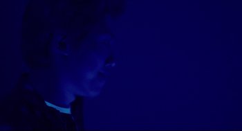 Movie still from “Millennium Mambo” (2001), directed by Hsiao-Hsien Hou – A man in a dark room with blue lighting; Close Up shot, Low angle