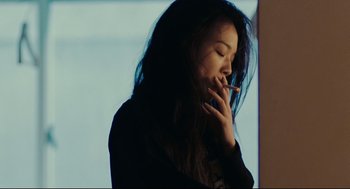 Movie still from “Millennium Mambo” (2001), directed by Hsiao-Hsien Hou – A woman smoking a cigarette in front of a window; Close Up shot, Over the shoulder angle