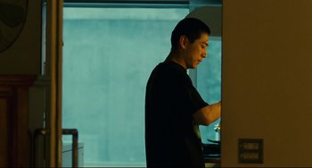 Movie still from “Millennium Mambo” (2001), directed by Hsiao-Hsien Hou – A man standing in front of a window looking at his cell phone; Medium shot, Low angle