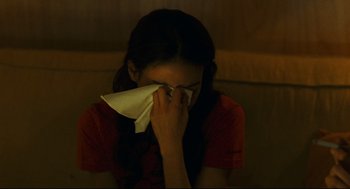 Movie still from “Millennium Mambo” (2001), directed by Hsiao-Hsien Hou – A woman sitting in front of a window holding a napkin to her face; Close Up shot, High angle