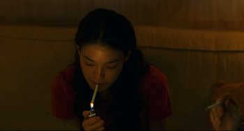 Movie still from “Millennium Mambo” (2001), directed by Hsiao-Hsien Hou – A woman is lighting a candle in a candle holder; Medium shot, High angle