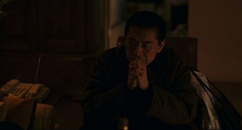 Movie still from “Millennium Mambo” (2001), directed by Hsiao-Hsien Hou – A man sitting in front of a candle in a dark room; Medium shot, High angle