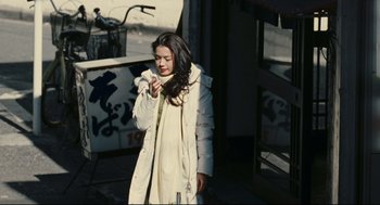 Movie still from “Millennium Mambo” (2001), directed by Hsiao-Hsien Hou – A woman in a white coat is standing on a sidewalk; Medium shot, Low angle