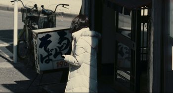 Movie still from “Millennium Mambo” (2001), directed by Hsiao-Hsien Hou – A woman in a white coat is standing outside; Wide shot, High angle
