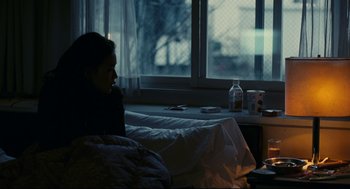 Movie still from “Millennium Mambo” (2001), directed by Hsiao-Hsien Hou – A person sitting in a bed in a room; Medium shot, Over the shoulder angle