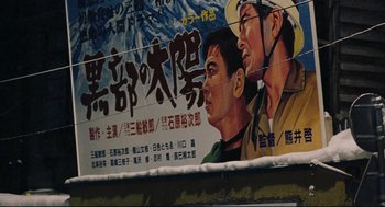 Movie still from “Millennium Mambo” (2001), directed by Hsiao-Hsien Hou – An advertisement of two asian men on the side of a building; Extreme Close Up shot, Low angle