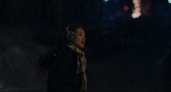 Movie still from “Millennium Mambo” (2001), directed by Hsiao-Hsien Hou – A woman wearing ear muffs while standing in the dark; Close Up shot, Over the shoulder angle