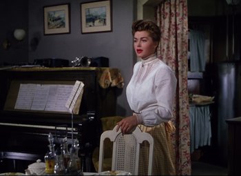 Movie still from “Million Dollar Mermaid” (1952), directed by Mervyn LeRoy – A woman standing in front of a table holding a chair; Medium shot, Low angle