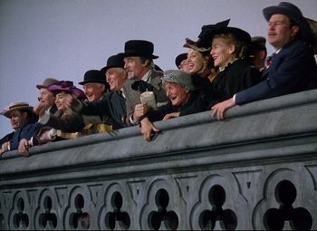 Movie still from “Million Dollar Mermaid” (1952), directed by Mervyn LeRoy – A group of people wearing hats and standing next to a fence; Wide shot, Low angle