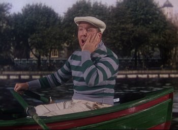 Movie still from “Million Dollar Mermaid” (1952), directed by Mervyn LeRoy – An older man in a striped sweater rowing a rowboat; Medium shot, High angle