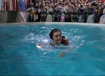 Movie still from “Million Dollar Mermaid” (1952), directed by Mervyn LeRoy – A woman swimming in a swimming pool while people watch; Medium shot, High angle