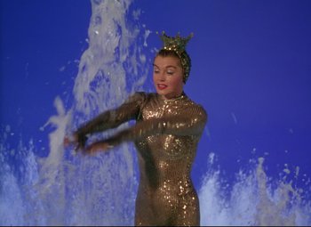Movie still from “Million Dollar Mermaid” (1952), directed by Mervyn LeRoy – A woman in a gold outfit standing in front of a fountain; Medium shot, Low angle