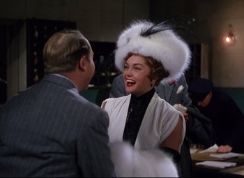 Movie still from “Million Dollar Mermaid” (1952), directed by Mervyn LeRoy – A woman wearing a white hat talking to an older man; Medium shot, Over the shoulder angle