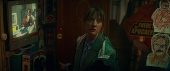 Movie still from “Mindhorn” (2016), directed by Sean Foley – A woman in a green jacket is standing in front of a door; Close Up shot, Over the shoulder angle