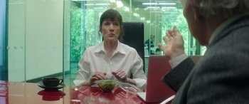 Movie still from “Mindhorn” (2016), directed by Sean Foley – A woman sitting at a table in front of a bowl of salad; Medium shot, Over the shoulder angle