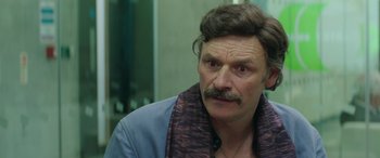 Movie still from “Mindhorn” (2016), directed by Sean Foley – A person with a mustache wearing a jacket; Close Up shot, Over the shoulder angle