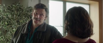 Movie still from “Mindhorn” (2016), directed by Sean Foley – A man with a mustache talking to a woman in front of a window; Close Up shot, Over the shoulder angle