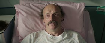 Movie still from “Mindhorn” (2016), directed by Sean Foley – A person laying in a hospital bed; Close Up shot, High angle