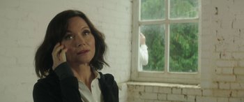 Movie still from “Mindhorn” (2016), directed by Sean Foley – A woman standing in front of an open window; Close Up shot, Over the shoulder angle